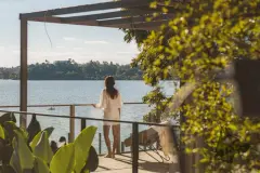 Foto real do deck com mulher olhando para a Baía Norte, cobertura em madeira e vegetação ao redor — D/Season Residence Club em João Paulo, Florianópolis
