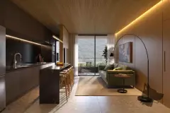 Perspectiva da cozinha com ilha de mármore, coifa e sala com sofá verde e vista para a varanda — Dália em Canasvieiras, Florianópolis