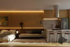Perspectiva do quarto integrado à sala e cozinha com ilha de mármore, cama e sofá com iluminação embutida — Dália em Canasvieiras, Florianópolis