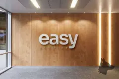 Parede com logotipo Easy Studios em letras brancas sobre revestimento de madeira com iluminação lateral dourada — Easy Studios em Centro, Florianópolis