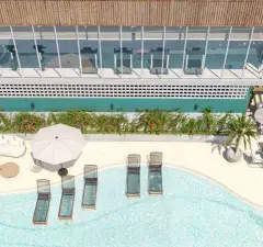 Vista aérea próxima da piscina com espreguiçadeiras, guarda-sol branco e academia envidraçada ao fundo — Gaivotas 4 em Ingleses, Florianópolis