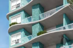 Detalhe da fachada com varandas onduladas em concreto, revestimento em pastilhas teal e plantas nas sacadas — Gaivotas 4 em Ingleses, Florianópolis