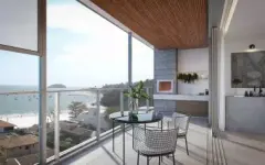 Varanda gourmet com mesa, cadeiras aramadas, churrasqueira e vista para a praia de Jurerê ao entardecer — Galleria 50 em Jurerê, Florianópolis