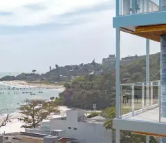 Vista da varanda para o mar de Jurerê com veleiros e morro verde ao fundo — Galleria 50 em Jurerê, Florianópolis