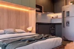 Studio decorado com cama de casal embutida com cabeceira iluminada e cozinha integrada com forno, geladeira e armários — Gran Malltech Business by Housi em Vargem Grande, Florianópolis