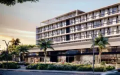 Fachada frontal do edifício ao entardecer com palmeiras, térreo comercial envidraçado e varandas nos andares superiores — Gran Malltech Business by Housi em Vargem Grande, Florianópolis