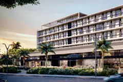 Fachada frontal do edifício ao entardecer com palmeiras e lojas no térreo, incluindo Root Kogeara, London e Urban Coffee — Gran Malltech Business by Housi em Vargem Grande, Florianópolis
