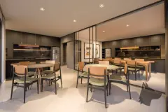 Salão de festas gourmet com mesas redondas, cadeiras amadeiradas, cozinha integrada escura e divisória de vidro — Gran Malltech Residence em Vargem Grande, Florianópolis