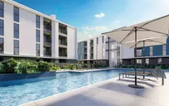 Área da piscina com deck, espreguiçadeiras e guarda-sol em ângulo panorâmico com os dois blocos ao fundo — Gran Malltech Residence em Vargem Grande, Florianópolis