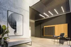 Lobby de entrada com obra de arte circular, painel de caixas de correspondência em madeira e banco estofado — Gran Malltech Residence em Vargem Grande, Florianópolis