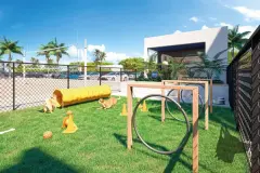 Pet place com gramado sintético, brinquedos para cães e cachorros brincando em dia ensolarado — Gran Malltech Residence em Vargem Grande, Florianópolis