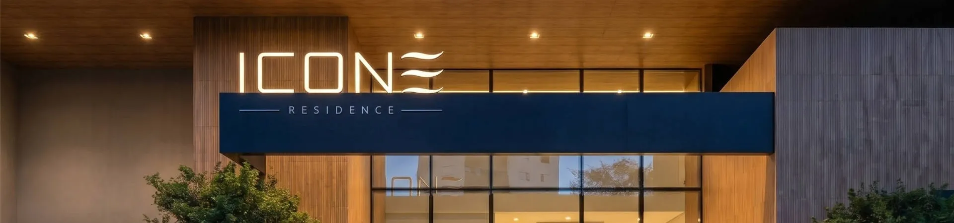 Fachada iluminada à noite com letreiro Icone Residence, entrada envidraçada e revestimento amadeirado — Icone Residence em Ingleses, Florianópolis