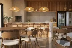 Salão de festas com mesas e cadeiras de madeira, bancada de churrasqueira, adega e pendentes de palha — Icone Residence em Ingleses, Florianópolis