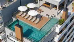 Vista aérea da piscina no rooftop com espreguiçadeiras, guarda-sol e área de convivência ao lado — Icone Residence em Ingleses, Florianópolis