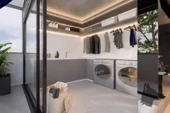 Render da lavanderia com bancada, araras, máquina de lavar e secar e abertura para varanda — Imob Canas em Canasvieiras, Florianópolis