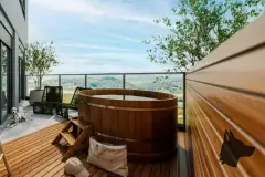 Varanda de cobertura com banheira de madeira tipo ofurô, espreguiçadeiras e vista para vegetação e montanhas — Imob Trindade On em Trindade, Florianópolis