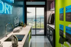 Lavanderia compartilhada com bancada, pias, máquinas de lavar, arara de roupas e paredes verdes com neon Laundry — Imob Trindade On em Trindade, Florianópolis