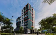 Fachada em perspectiva lateral, torre de 9 andares com revestimento verde e detalhes vermelhos nas varandas — Imob Trindade On em Trindade, Florianópolis