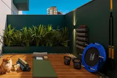 Área de yoga e fitness ao ar livre com tapetes de exercício, kettlebells, trampolim e parede em verde musgo — Imob Trindade On em Trindade, Florianópolis