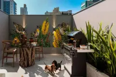 Área gourmet com mesa rústica, churrasqueira, mural de pássaros e flores amarelas, dois dachshunds no pátio — Imob Trindade On em Trindade, Florianópolis
