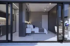 Interior de studio visto pela porta de vidro da sacada, com cama de casal, escrivaninha e cozinha integrada ao fundo — Imperial Residence em Campeche, Florianópolis