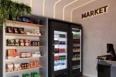 Mini market com prateleiras de produtos, geladeiras de bebidas e letreiro Market iluminado em dourado — In Haus Afonso Pena em Canto, Florianópolis
