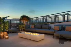 Rooftop lounge ao entardecer com sofás cinza, lareira linear de fogo e plantas tropicais ao pôr do sol — In Haus Afonso Pena em Canto, Florianópolis