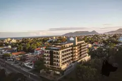 Vista aérea do edifício ao entardecer com o bairro Campeche, o mar e o morro ao fundo — Infinite Campeche em Campeche, Florianópolis