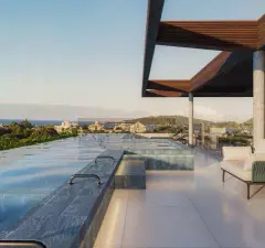 Piscina no rooftop com água iluminada, espreguiçadeira e vista para o bairro ao entardecer — Infinite Campeche em Campeche, Florianópolis