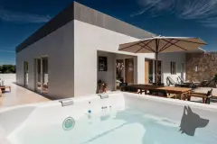 Área de lazer com banheira de hidromassagem externa, mesa de jantar com guarda-sol e cadeiras reclináveis ao fundo — Infinity Residence em Ingleses, Florianópolis