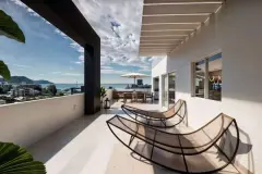 Terraço com vista para o mar e cidade, espreguiçadeiras de fibra e mesa de jantar com guarda-sol — Infinity Residence em Ingleses, Florianópolis