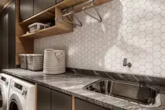 Lavanderia com bancada de mármore cinza, revestimento hexagonal branco, prateleiras e tanque inox — Infinity Residence em Ingleses, Florianópolis