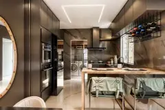 Cozinha com armários escuros, ilha com tampo de madeira, adega suspensa e visão para lavanderia — Infinity Residence em Ingleses, Florianópolis