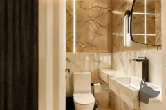 Lavabo com revestimento de mármore dourado, vaso sanitário, cuba esculpida e espelho com LED — Infinity Residence em Ingleses, Florianópolis