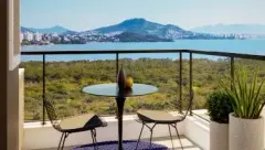 Varanda com mesa e cadeiras com vista para a Baía Norte e morros de Florianópolis — Jardim Cacupé Residence em Cacupé, Florianópolis