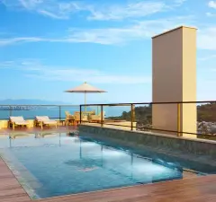 Piscina no rooftop com deck de madeira, espreguiçadeiras e vista para a Baía Norte — Jardim Cacupé Residence em Cacupé, Florianópolis