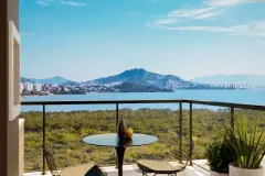 Varanda com mesa e cadeiras com vista para a Baía Norte, morros e vegetação nativa de Cacupé — Jardim Cacupé Residence em Cacupé, Florianópolis