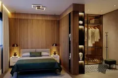 Suíte com cama de casal, painel ripado em madeira e closet com portas de vidro iluminado — Jardim Cacupé Residence em Cacupé, Florianópolis