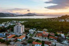 Vista aérea ao pôr do sol do empreendimento no bairro Cacupé com Baía Norte e morros ao fundo — Jardim Cacupé Residence em Cacupé, Florianópolis