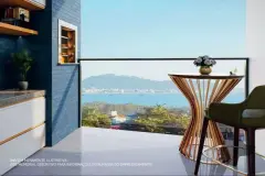 Perspectiva da varanda com mesa e cadeira e vista para o mar e montanhas em Ponta das Canas — Lazuli Residence em Ponta das Canas, Florianópolis