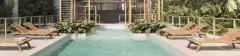 Perspectiva ilustrativa da piscina com espreguiçadeiras de madeira, plantas tropicais e pérgola ao fundo — Lumina Residence em Cachoeira do Bom Jesus, Florianópolis