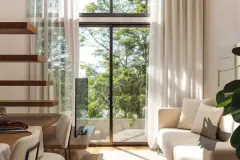 Perspectiva da sala de estar com sofá claro, escada de madeira e vista para jardim, ângulo alternativo — Lunáh Blue View em Campeche, Florianópolis