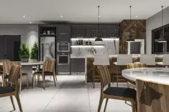 Cozinha gourmet do salão de festas com armários cinza, ilha com banquetas, adega e mesas de jantar ao fundo — Manhattan Residence em Ingleses, Florianópolis