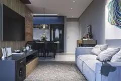Sala de estar do apartamento com sofá cinza, painel de TV em madeira, mesa de jantar preta e cozinha ao fundo — Manhattan Residence em Ingleses, Florianópolis