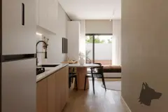 Cozinha americana com armários brancos e amadeirados, mesa redonda e sofá ao fundo — Mar do Norte Studios em Ingleses, Florianópolis