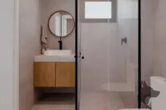 Banheiro com box de vidro transparente, bancada em terrazzo e espelho redondo — Mar do Norte Studios em Ingleses, Florianópolis