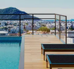 Piscina no rooftop com deck de madeira e espreguiçadeiras, vista para Ingleses e morros — Mar do Norte Studios em Ingleses, Florianópolis
