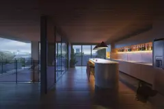 Cozinha da cobertura iluminada à noite com ilha em mármore, bar e varanda — Marena em Canasvieiras, Florianópolis