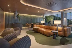 Lounge social com sofá de couro caramelo, poltronas, tapete verde orgânico e copa ao fundo — Max Studios 177 em Pantanal, Florianópolis