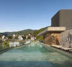 Piscina linear do rooftop com espreguiçadeiras e guarda-sóis listrados, formato retrato — Max Studios 177 em Pantanal, Florianópolis